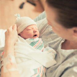 Newborn baby in the arms of her mother who has postpartum urinary incontinence | CU Medicine OB-GYN East Denver (Rocky Mountain) | Denver, CO